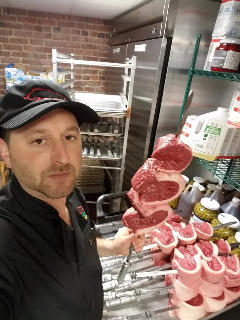 Chef Joe with cuts of meat in a restaurant kitchen