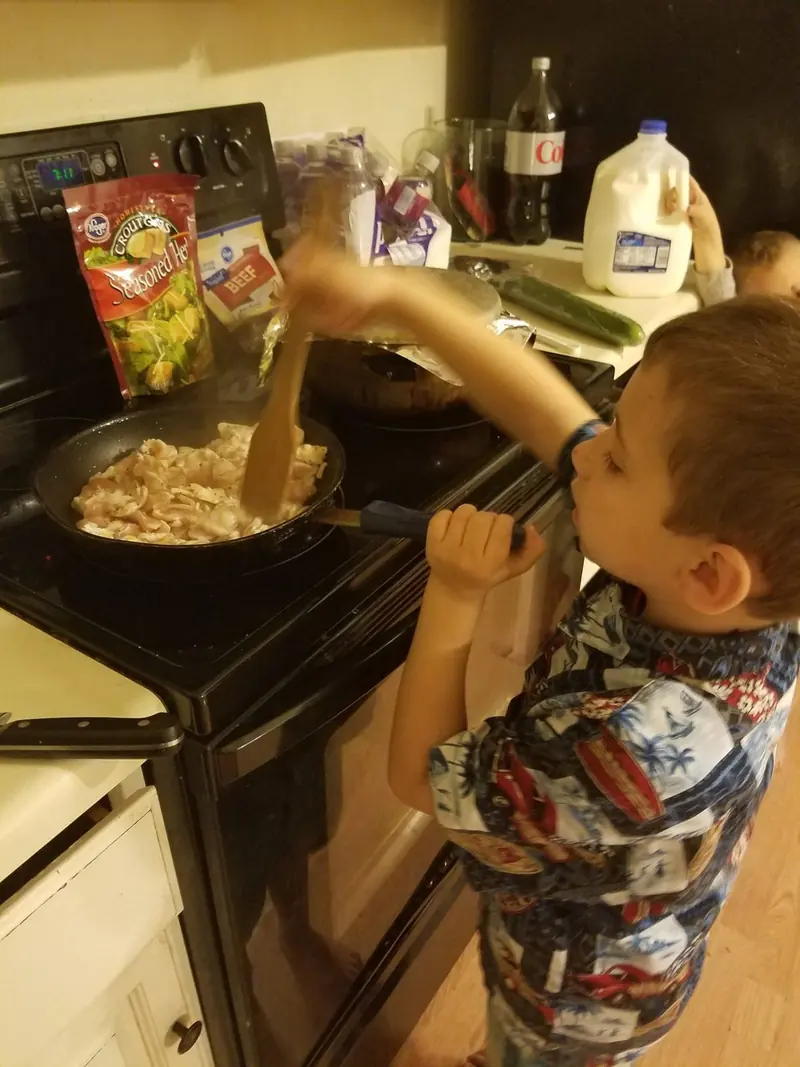 Chef Joe’s son as a young boy stirring a pot at the stove