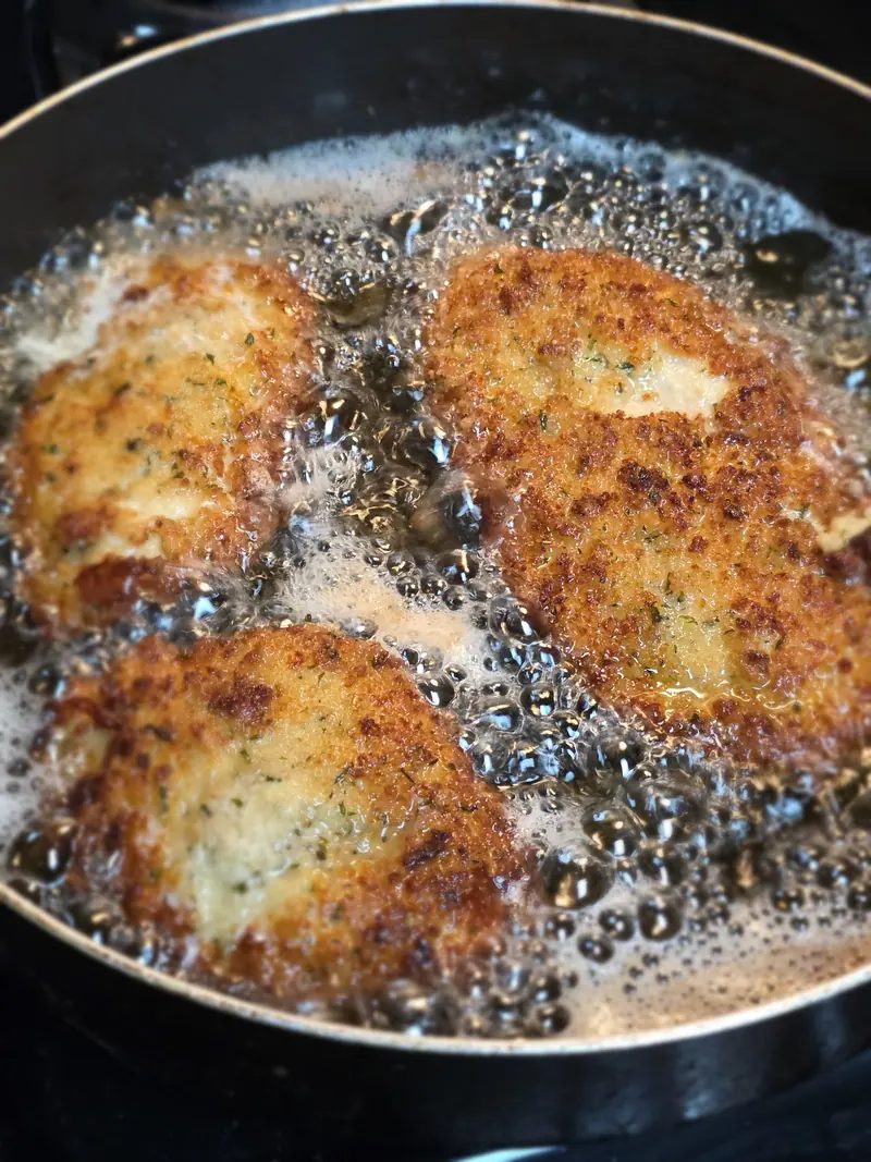 Breaded chicken frying in a skillet