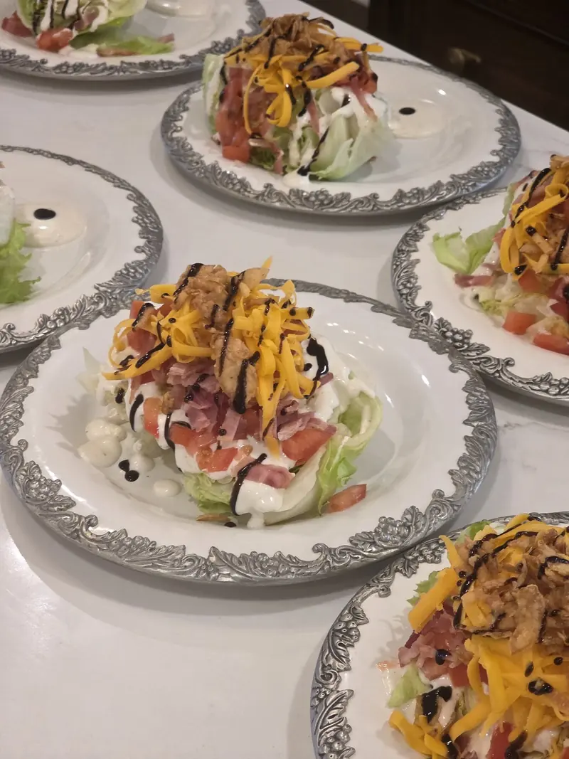 Loaded wedge salads plated on vintage china, lined up for service